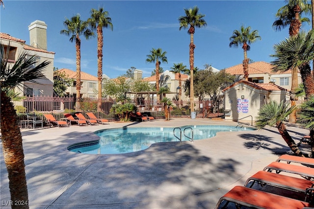 pool with a patio area and fence