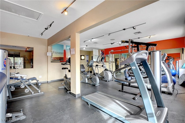 gym featuring baseboards, visible vents, and track lighting