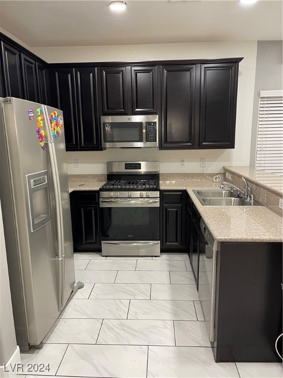 kitchen featuring light stone counters, sink, and stainless steel appliances