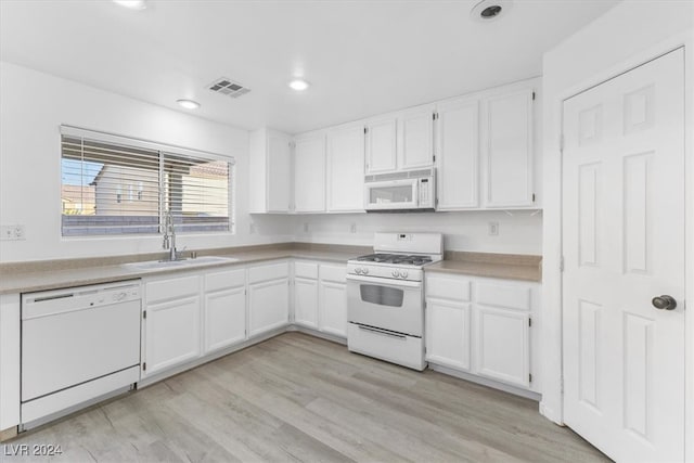 kitchen with white appliances, white cabinetry, sink, and light hardwood / wood-style floors