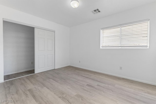 unfurnished bedroom with a closet and light wood-type flooring