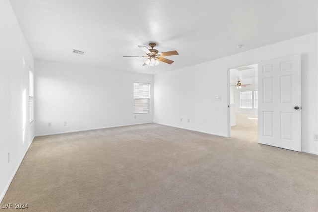 spare room featuring a wealth of natural light, ceiling fan, and light carpet