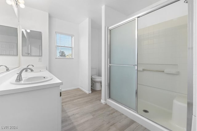 bathroom featuring hardwood / wood-style floors, vanity, toilet, and a shower with door