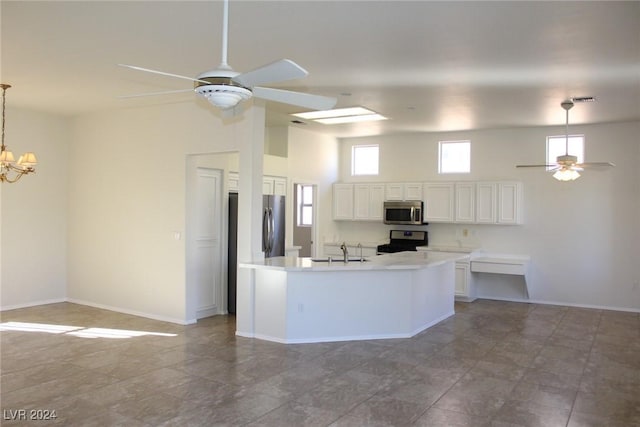 kitchen featuring stainless steel appliances, hanging light fixtures, a towering ceiling, sink, and white cabinetry