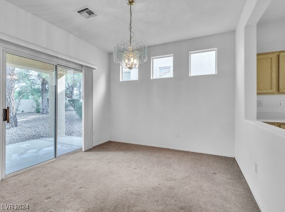 empty room featuring plenty of natural light, a notable chandelier, and light carpet