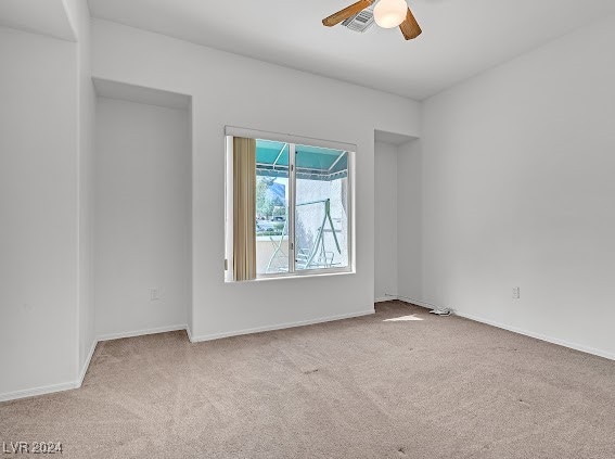 empty room featuring ceiling fan and light carpet