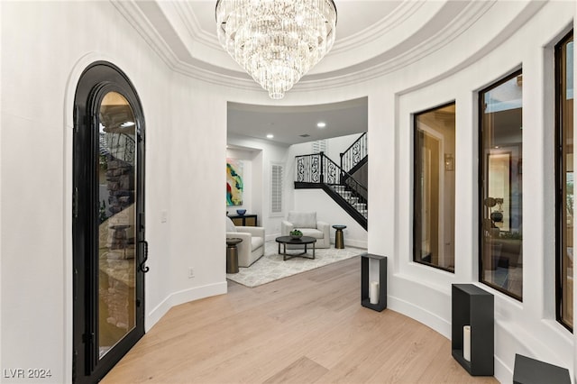 hall featuring light wood-type flooring, crown molding, and a tray ceiling