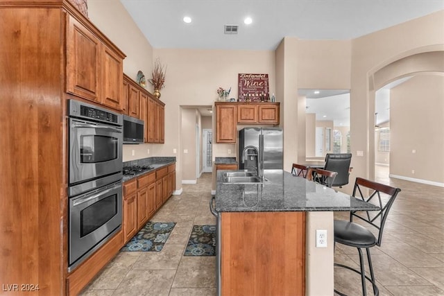 3689 Callahan Ave, Las Vegas, NV 89120 - kitchen featuring a sink, stainless steel appliances, arched walkways, a breakfast bar, and brown cabinets