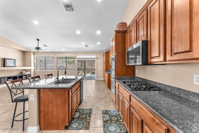 kitchen with ceiling fan, a breakfast bar area, a center island with sink, sink, and appliances with stainless steel finishes