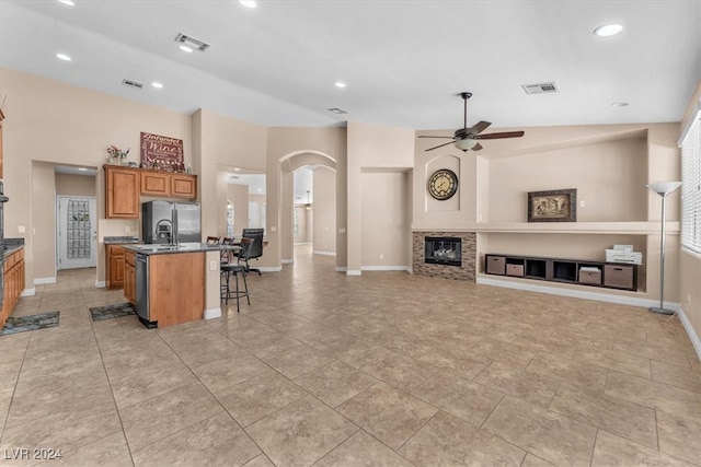 kitchen with a kitchen island with sink, ceiling fan, a breakfast bar area, vaulted ceiling, and stainless steel refrigerator with ice dispenser