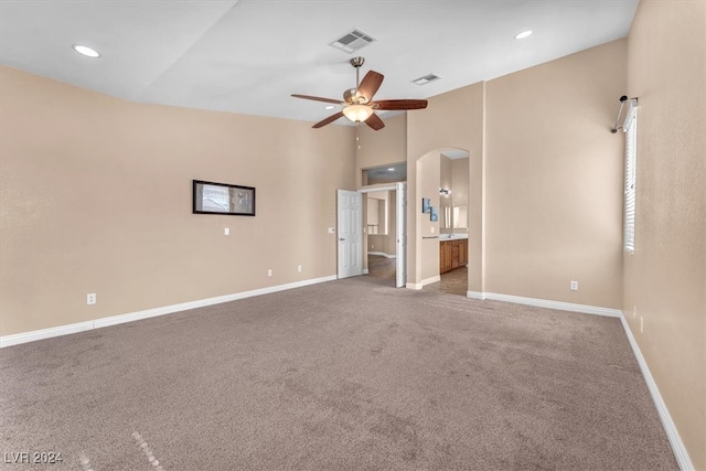 carpeted spare room featuring ceiling fan and a high ceiling