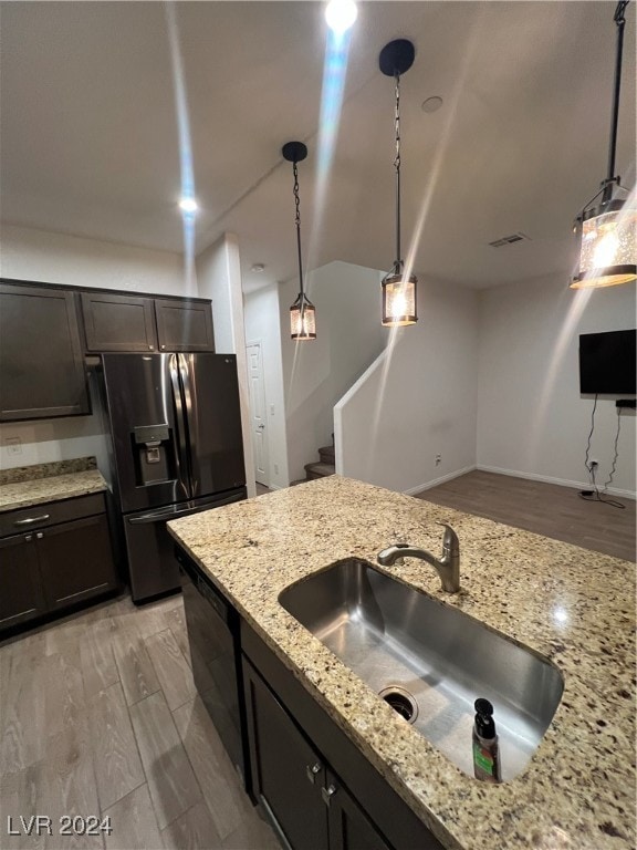 kitchen with dark brown cabinetry, stainless steel fridge, sink, decorative light fixtures, and light hardwood / wood-style floors