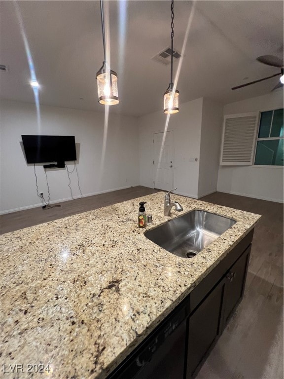 kitchen with light stone countertops, dark wood-type flooring, hanging light fixtures, and sink