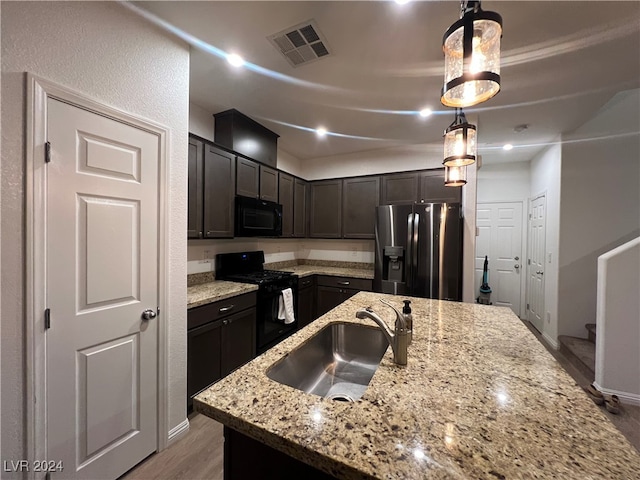 kitchen with dark hardwood / wood-style floors, a center island with sink, sink, hanging light fixtures, and black appliances