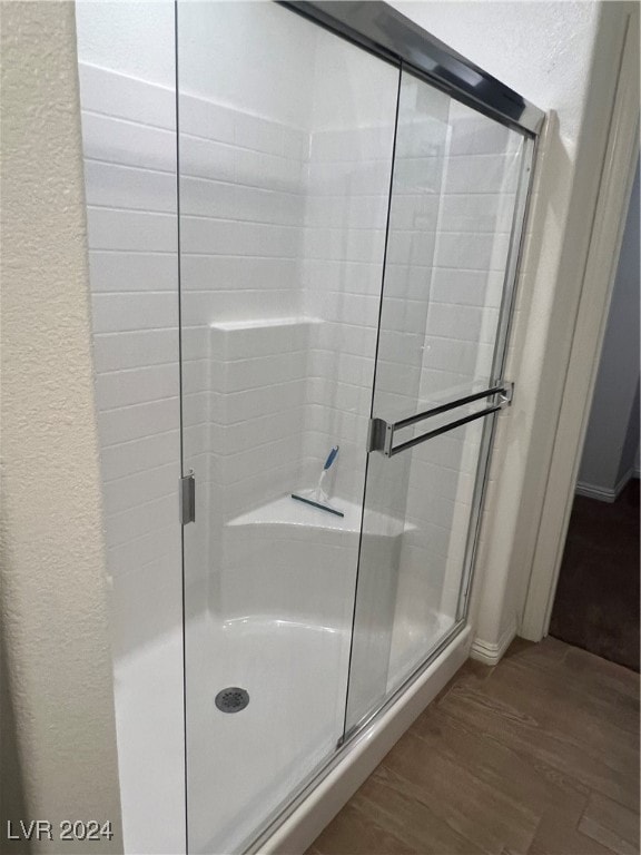 bathroom featuring wood-type flooring and a shower with shower door