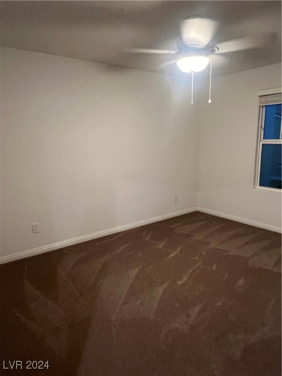 spare room featuring dark carpet and ceiling fan