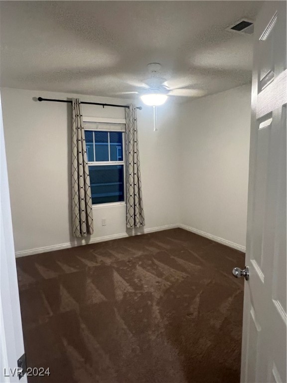 carpeted empty room with ceiling fan and a textured ceiling