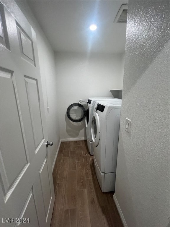 clothes washing area featuring dark hardwood / wood-style floors and washer and dryer