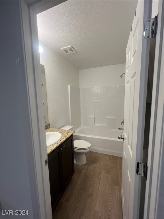 full bathroom featuring toilet, shower / bathing tub combination, hardwood / wood-style flooring, vanity, and a textured ceiling