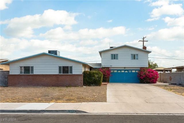 view of front of house featuring a garage, brick siding, driveway, and fence
