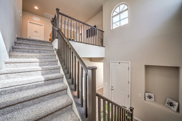 staircase featuring a high ceiling and carpet flooring