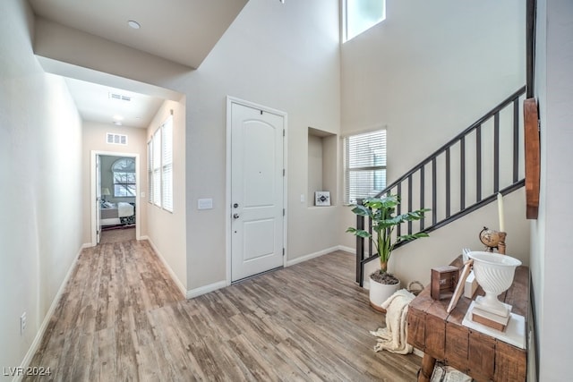 foyer with light wood-type flooring, a high ceiling, and a wealth of natural light