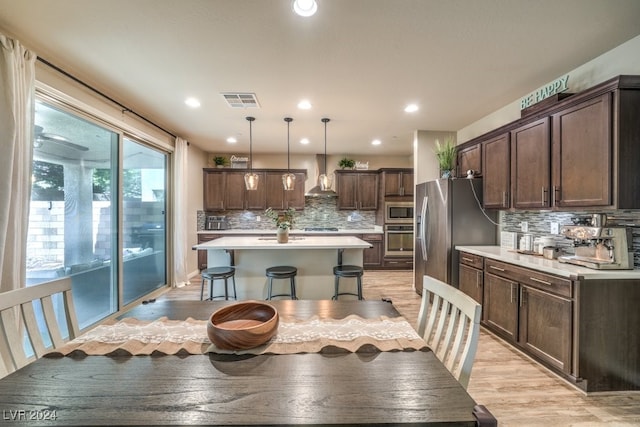 kitchen featuring a kitchen island, dark brown cabinets, decorative light fixtures, backsplash, and appliances with stainless steel finishes