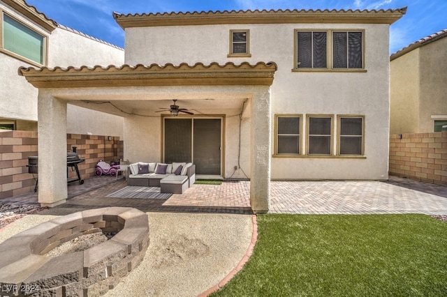 back of house featuring ceiling fan, a patio, and an outdoor living space with a fire pit