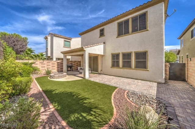 back of property with a yard and a patio