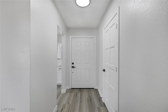 hallway featuring a textured ceiling and light wood-type flooring