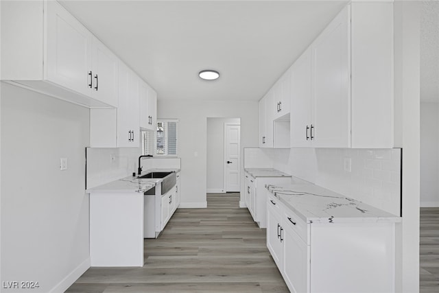 kitchen featuring light hardwood / wood-style floors, decorative backsplash, white cabinetry, and light stone counters