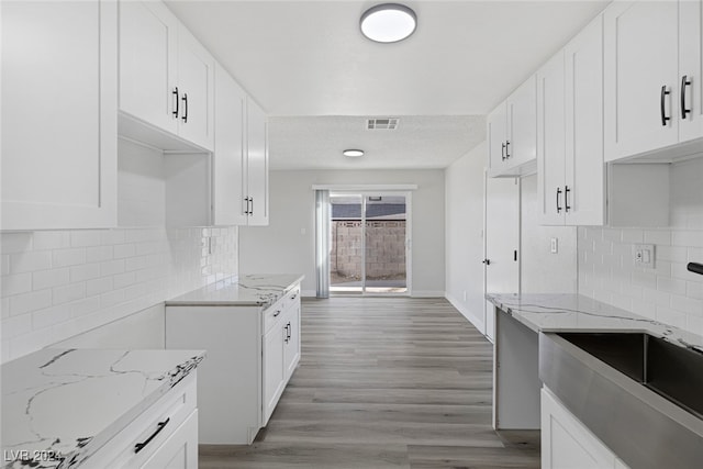 kitchen featuring light stone countertops, white cabinets, and light wood-type flooring