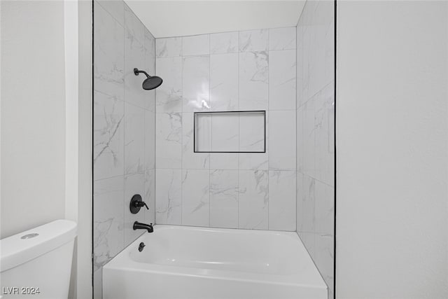 bathroom featuring tiled shower / bath combo and toilet