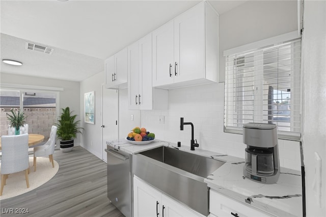 kitchen with white cabinetry, light hardwood / wood-style flooring, dishwasher, sink, and light stone counters