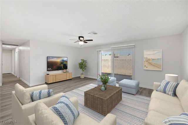 living room with a textured ceiling, wood-type flooring, and ceiling fan