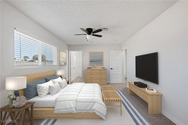 carpeted bedroom with ceiling fan and a textured ceiling