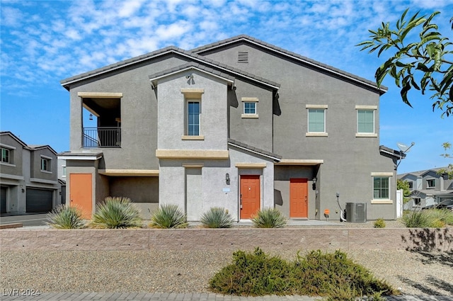 view of front facade featuring a garage, a balcony, and central AC