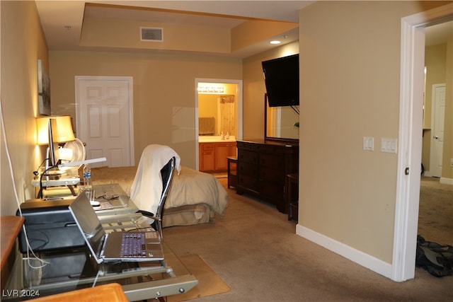 carpeted bedroom with ensuite bathroom and a tray ceiling