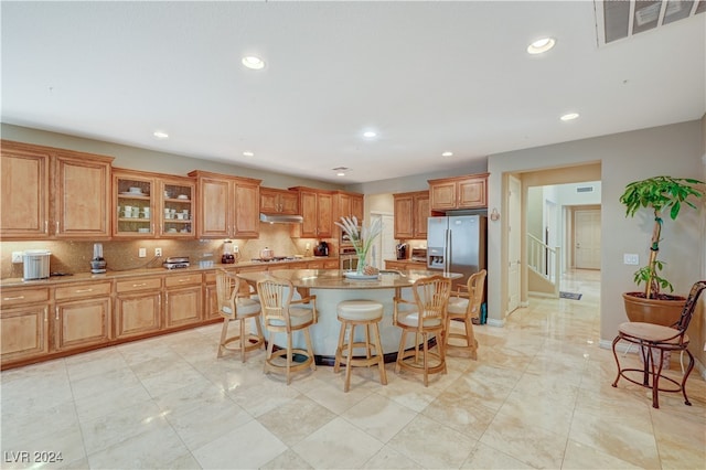 kitchen with stainless steel appliances, tasteful backsplash, a kitchen breakfast bar, and a center island