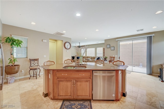 kitchen with an island with sink, light stone counters, and sink