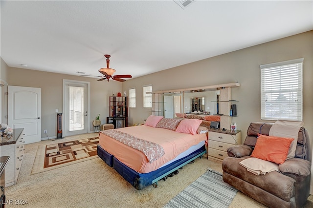 carpeted bedroom featuring multiple windows and ceiling fan