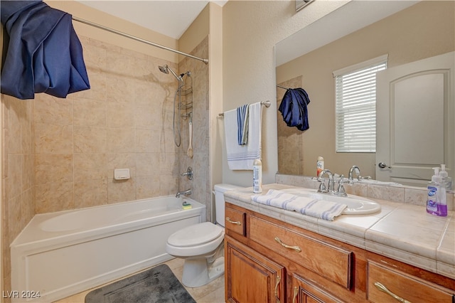 full bathroom with tiled shower / bath, tile patterned floors, vanity, and toilet