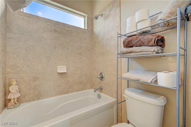 bathroom with tiled shower / bath combo and toilet