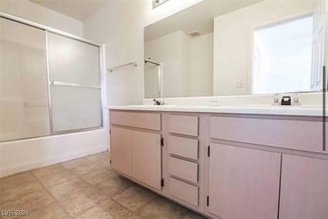 bathroom with a sink, enclosed tub / shower combo, and double vanity