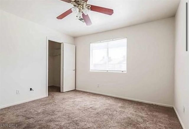 carpeted empty room featuring a ceiling fan and baseboards