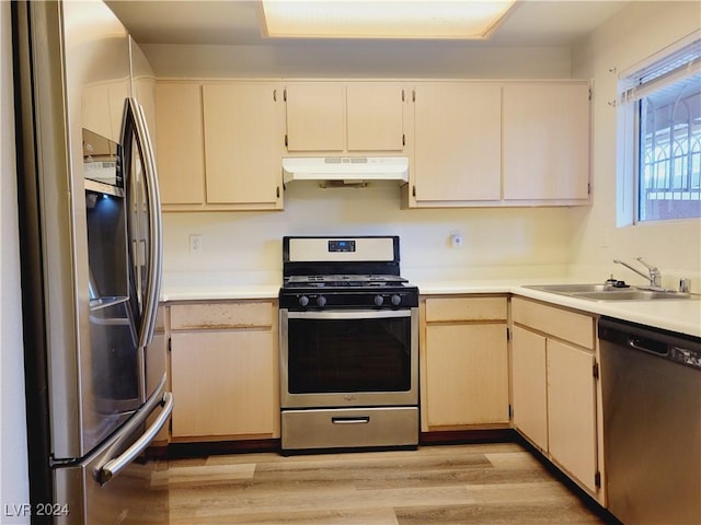 kitchen featuring under cabinet range hood, a sink, stainless steel appliances, light wood-style floors, and light countertops