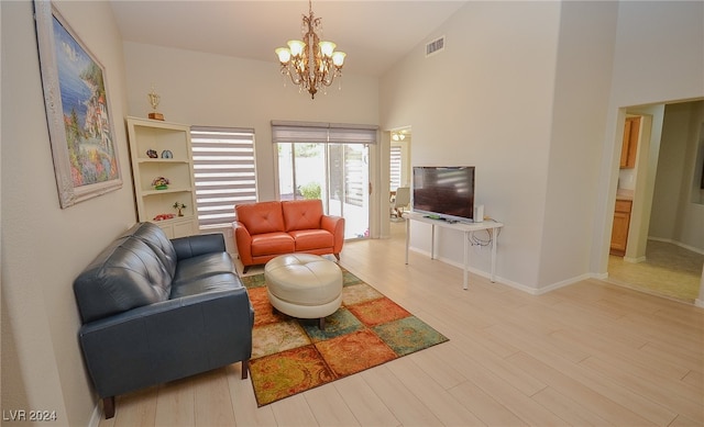 living room with an inviting chandelier, light hardwood / wood-style flooring, and high vaulted ceiling