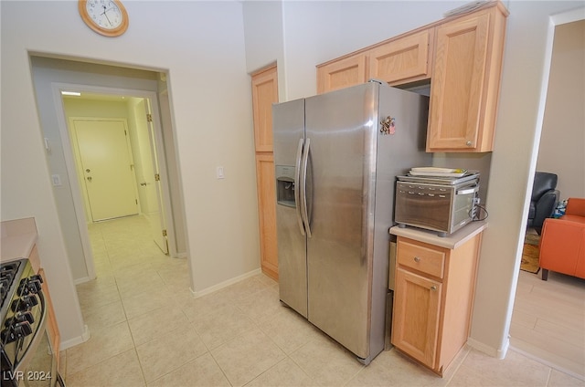 kitchen with light brown cabinets, appliances with stainless steel finishes, and light tile patterned floors