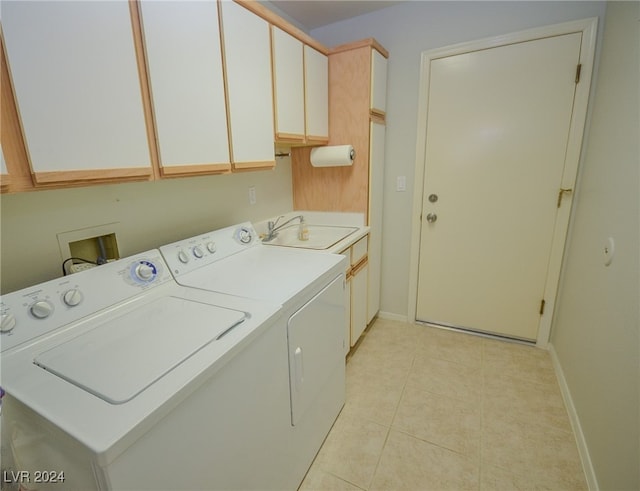 laundry room featuring washing machine and dryer, sink, light tile patterned flooring, and cabinets