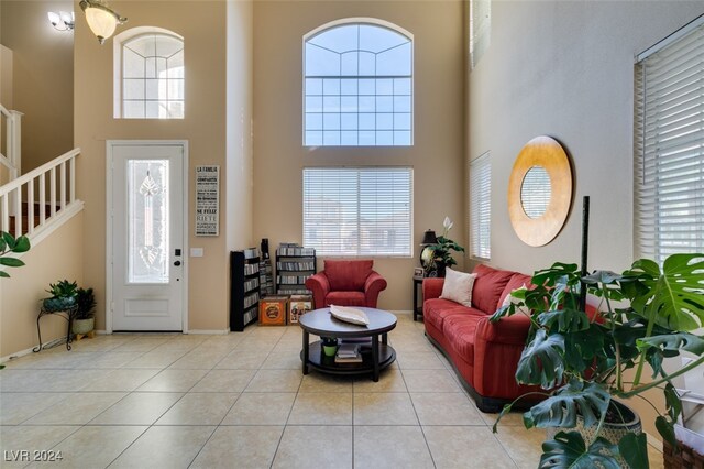 living room with light tile patterned flooring, a wealth of natural light, and a high ceiling